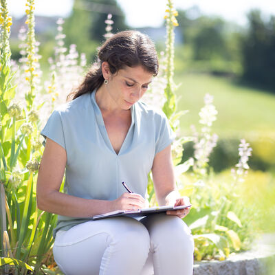 Bild zeigt Elisabeth Lerchbaum im Park wie sie einen Artikel für ihren Blog schreibt.