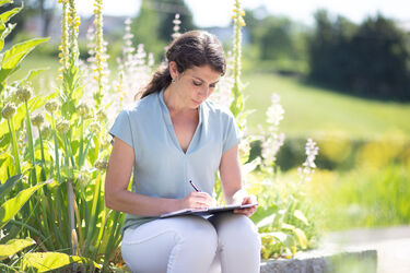 Bild zeigt Elisabeth Lerchbaum im Park wie sie einen Artikel für ihren Blog schreibt.