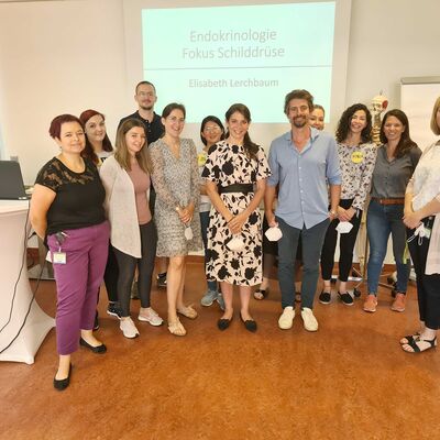 Bild zeigt Gruppe von Menschen die einen Vortrag halten.